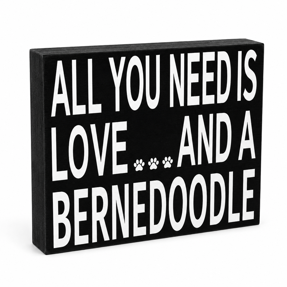 A rectangular black wooden sign with bold white text reading 'ALL YOU NEED IS LOVE.