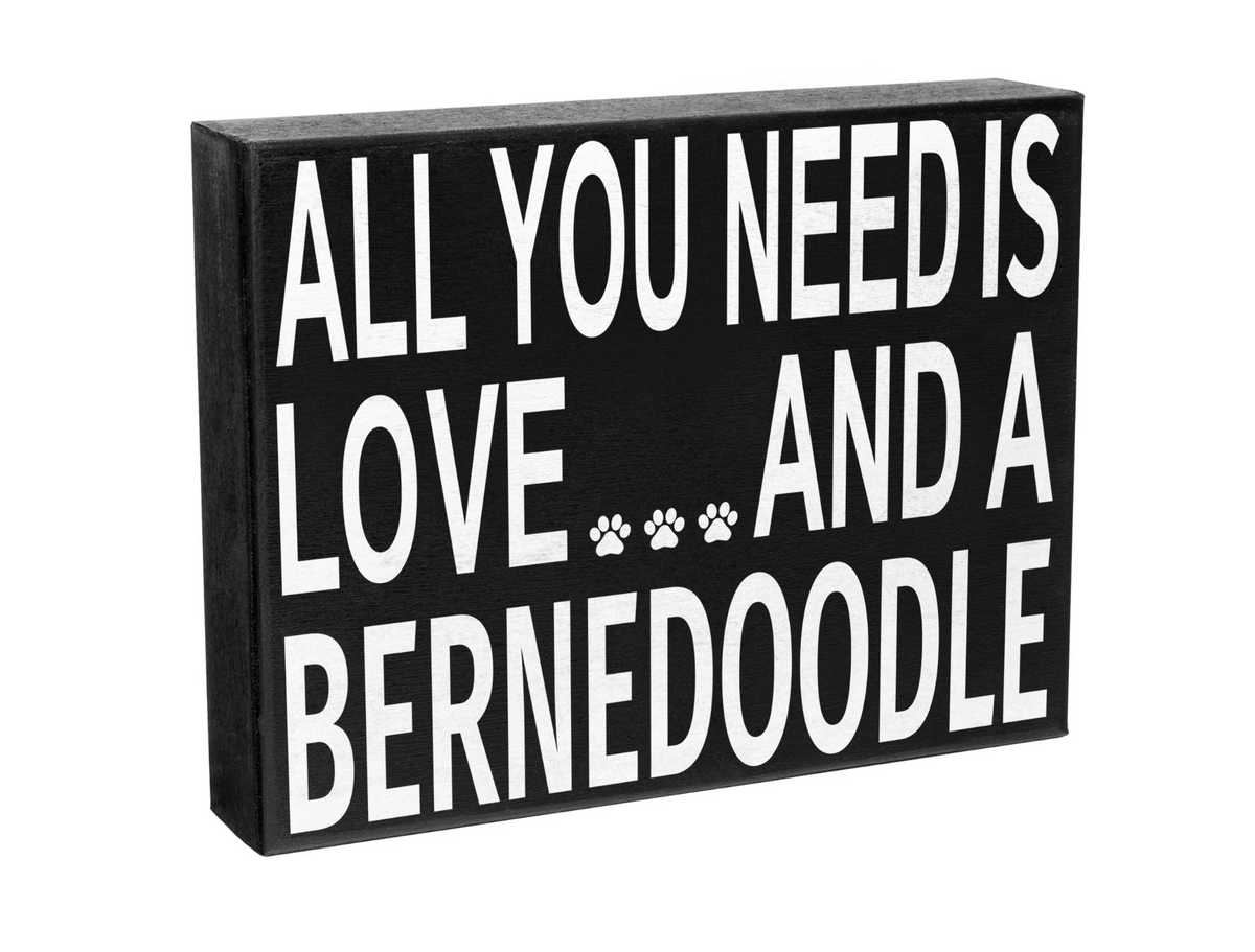 Decorative sign with text 'All you need is love and a Bernedoodle' on a white background