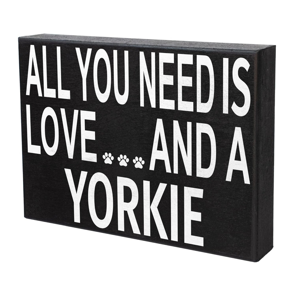 A rectangular black decorative sign with bold white text reading 'ALL YOU NEED IS LOVE.