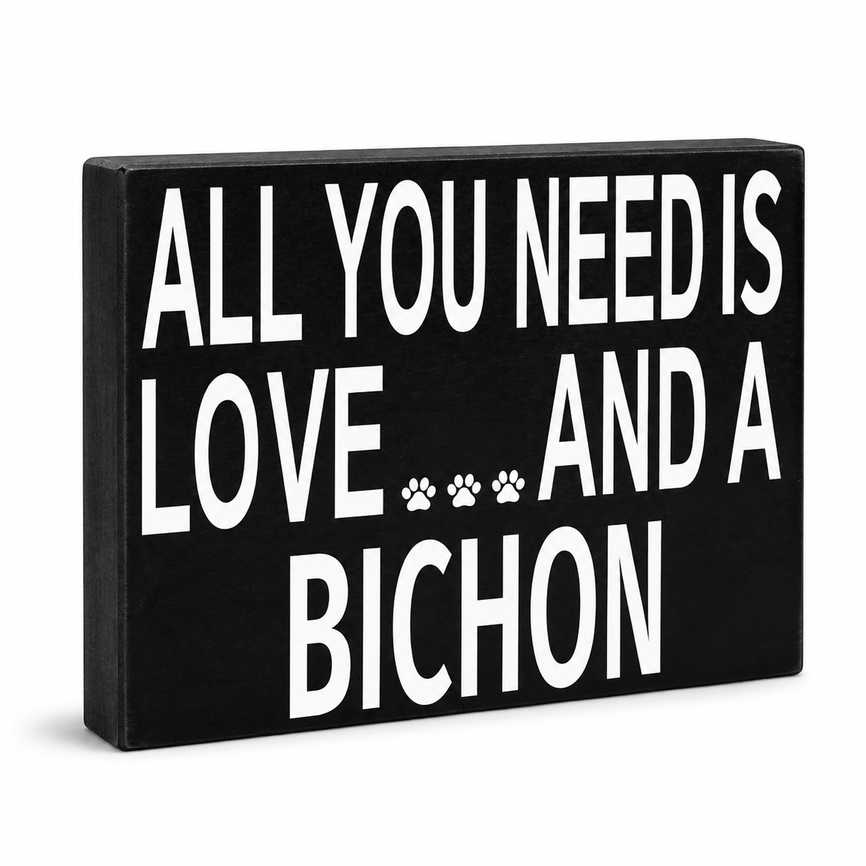 A rectangular black decorative sign with bold white text reading 'ALL YOU NEED IS LOVE.