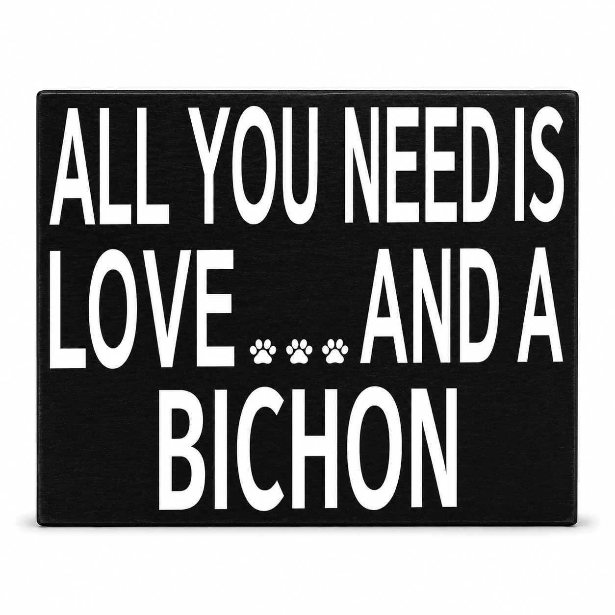 A rectangular black sign with bold white text reading 'ALL YOU NEED IS LOVE.