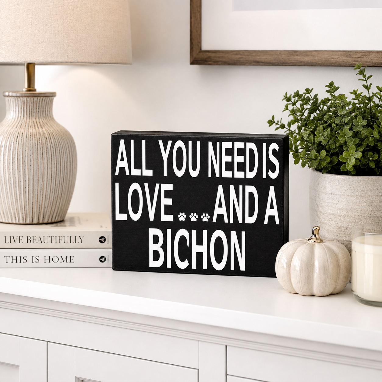 A black rectangular decorative sign with bold white text reading 'ALL YOU NEED IS LOVE.
