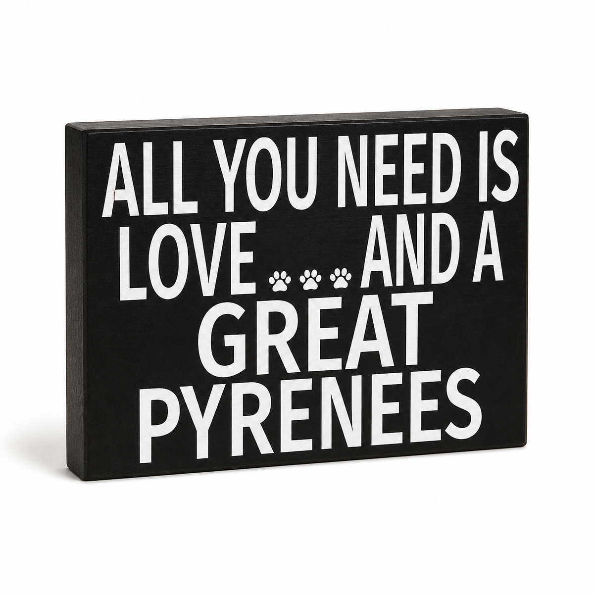 A rectangular black decorative sign with bold white text reading 'ALL YOU NEED IS LOVE.