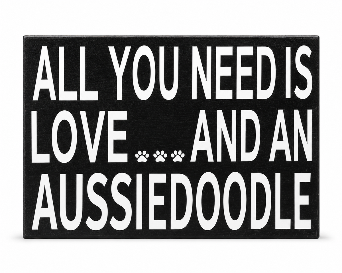 A rectangular black sign with bold white text reading 'ALL YOU NEED IS LOVE.