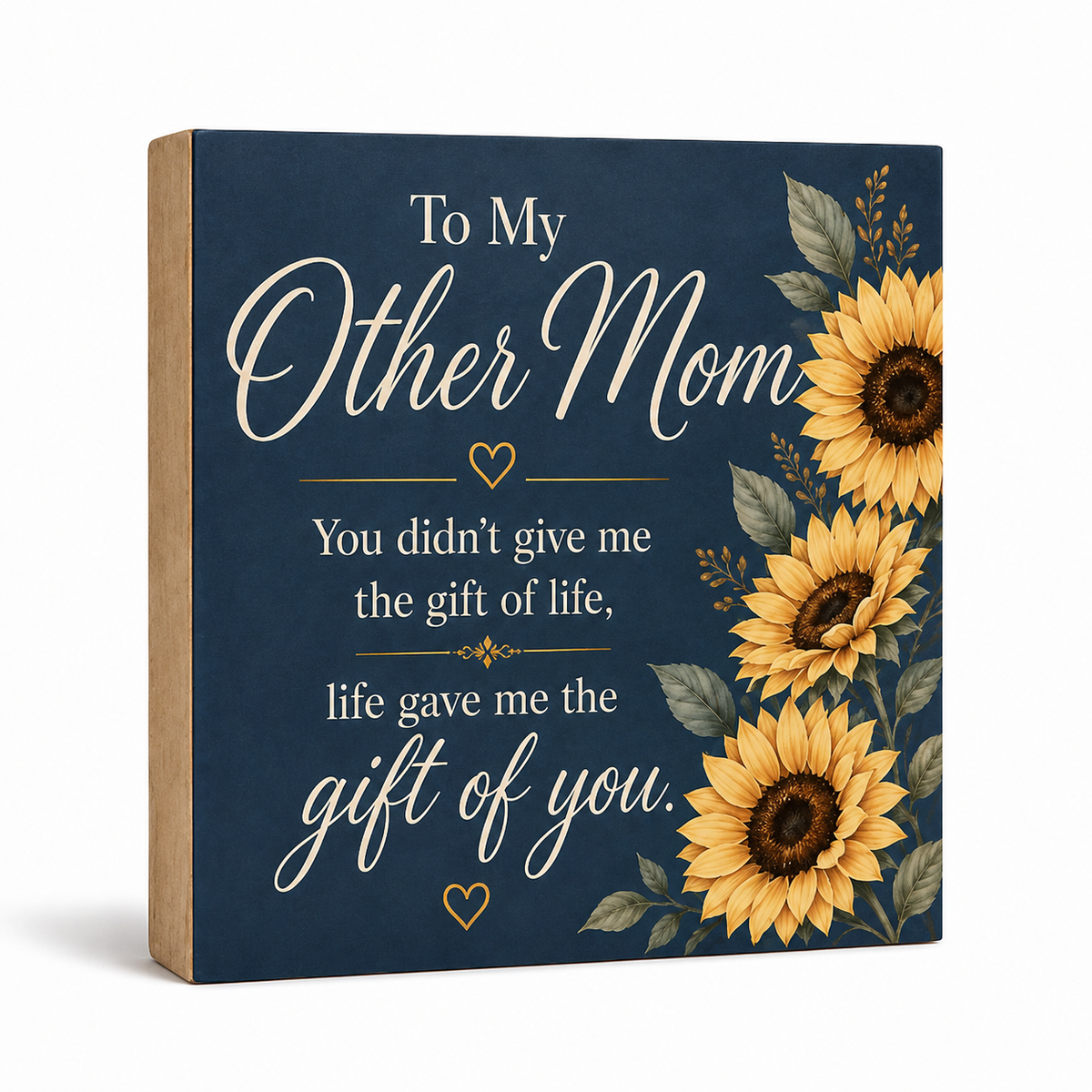 A square decorative wooden sign with a navy blue front, featuring the phrase 'To My Other Mom' in white script and serif text, surrounded by yellow sunflowers and green leaves on the right side. The left side shows the natural wood edge of the sign.