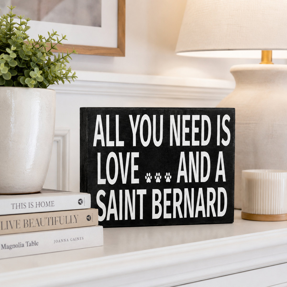 A black rectangular decorative sign with white text reading 'ALL YOU NEED IS LOVE.