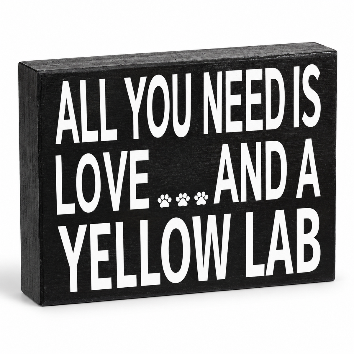 A rectangular black wooden sign with bold white text reading 'ALL YOU NEED IS LOVE.
