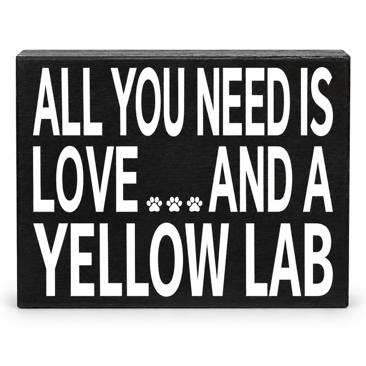 A rectangular black wooden sign with bold white text reading 'ALL YOU NEED IS LOVE.