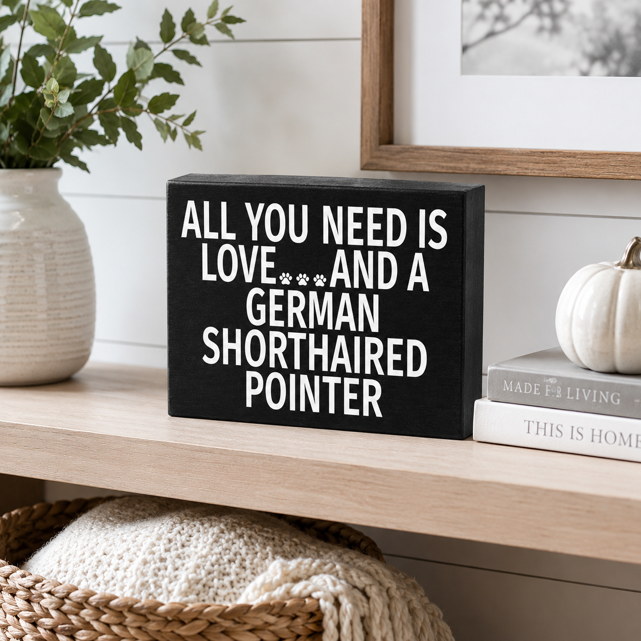 A black rectangular decorative sign with white text reading 'ALL YOU NEED IS LOVE.