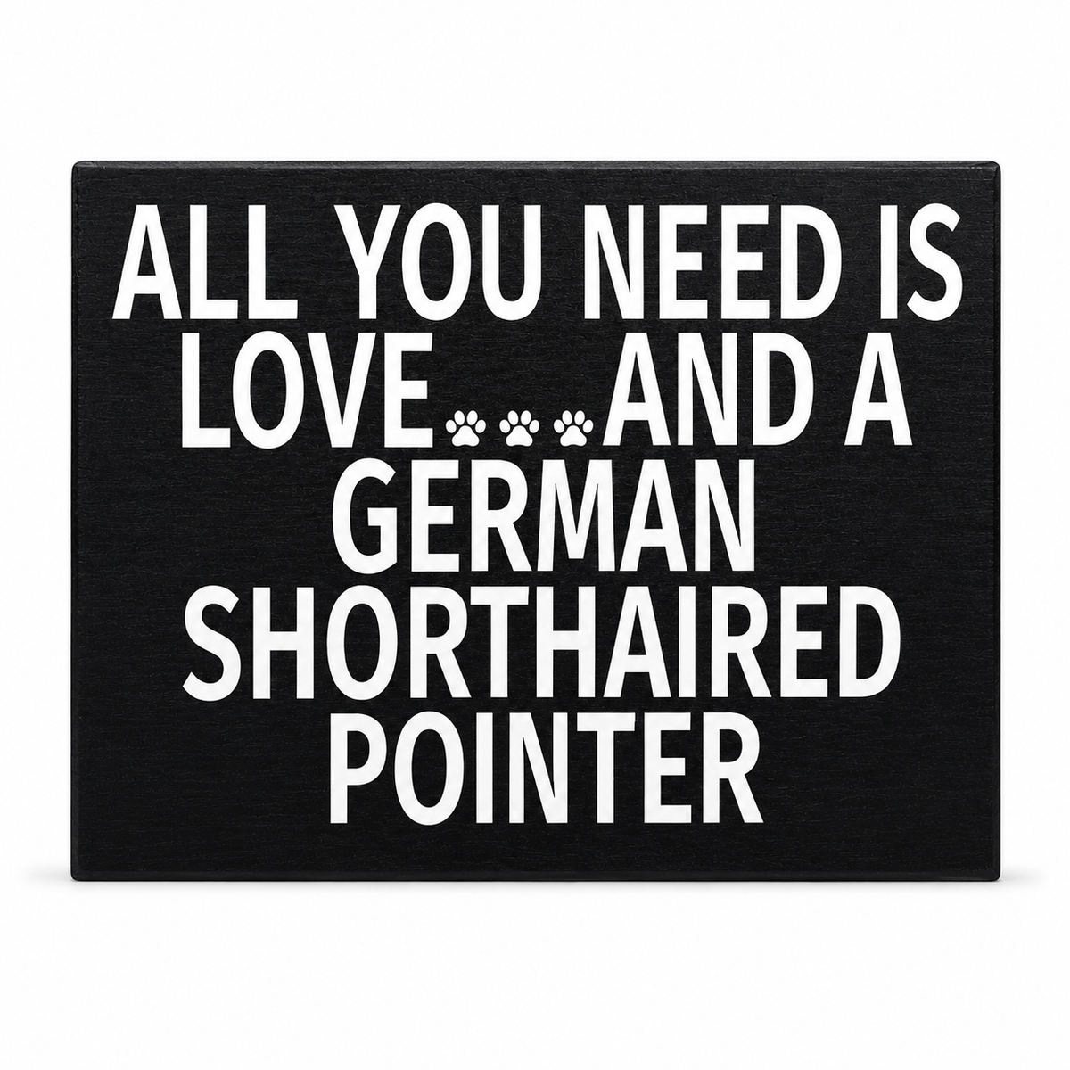 A rectangular black plaque or sign with bold white text reading 'ALL YOU NEED IS LOVE.