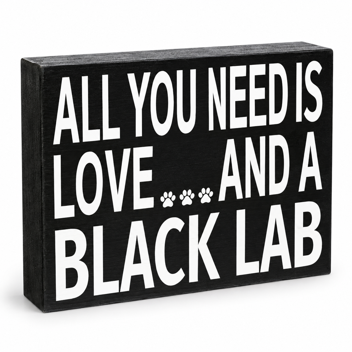 A rectangular black wooden sign with bold white text reading 'ALL YOU NEED IS LOVE.