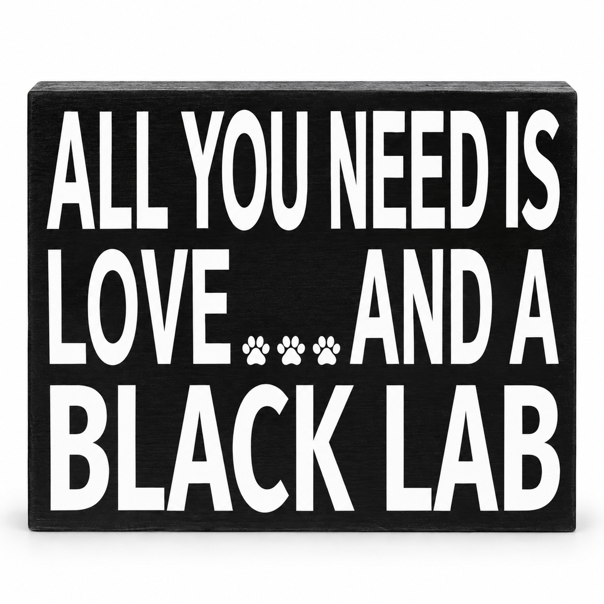A rectangular black decorative sign with bold white text reading 'ALL YOU NEED IS LOVE.