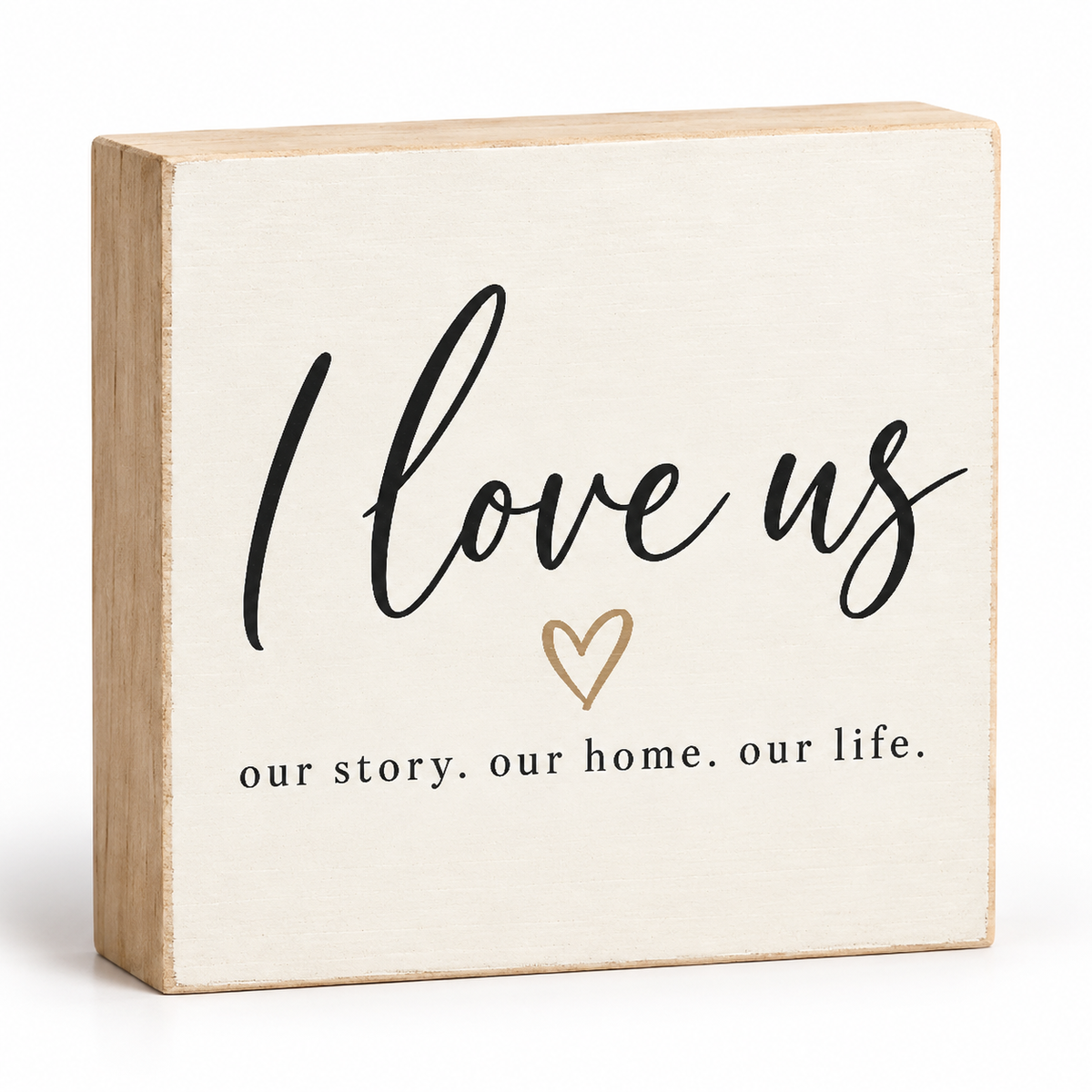 A square wooden block sign with a cream-colored face and natural light wood edges. The front is printed with the phrase 'I love us' in black script, a small gold heart, and the text 'our story.