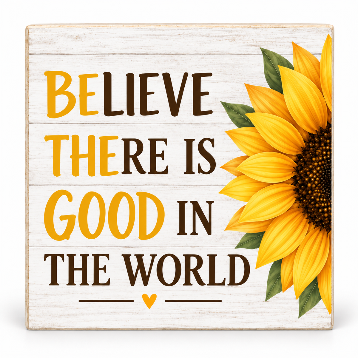 A square decorative wooden sign with a whitewashed wood texture, featuring the text 'BELIEVE THERE IS GOOD IN THE WORLD' in yellow and dark brown lettering, alongside a large yellow sunflower with green leaves on the right side.