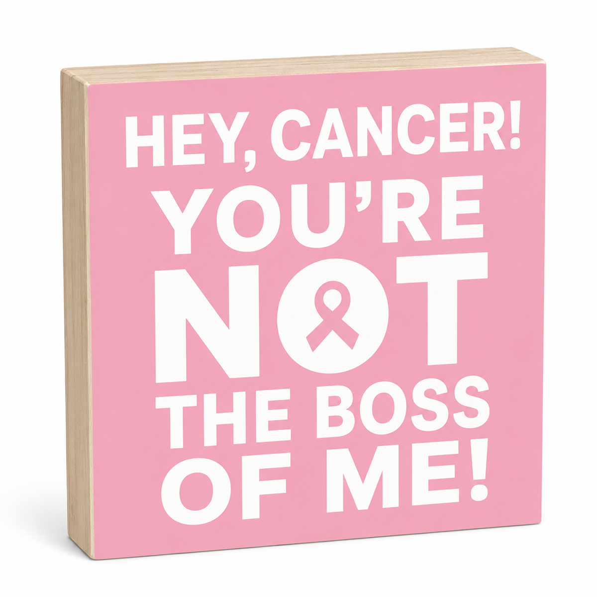 A square wooden sign with a pink face and natural wood edges, printed with the phrase 'HEY, CANCER! YOU'RE NOT THE BOSS OF ME!' in bold white text, including a pink ribbon inside the letter O.