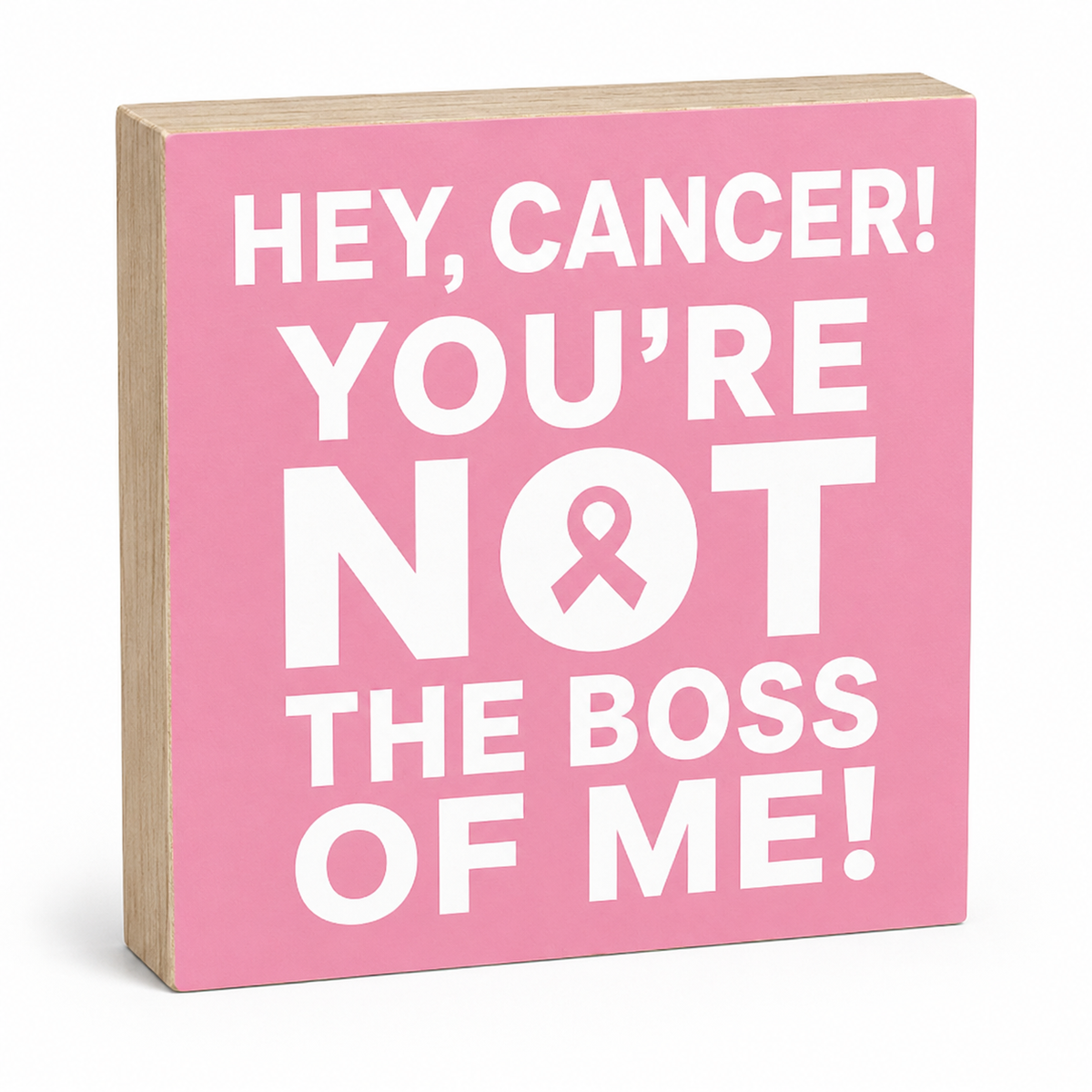 A square wooden sign with a pink face and natural wood edges, printed with the phrase 'HEY, CANCER! YOU'RE NOT THE BOSS OF ME!' in bold white text, including a pink ribbon inside the letter O.