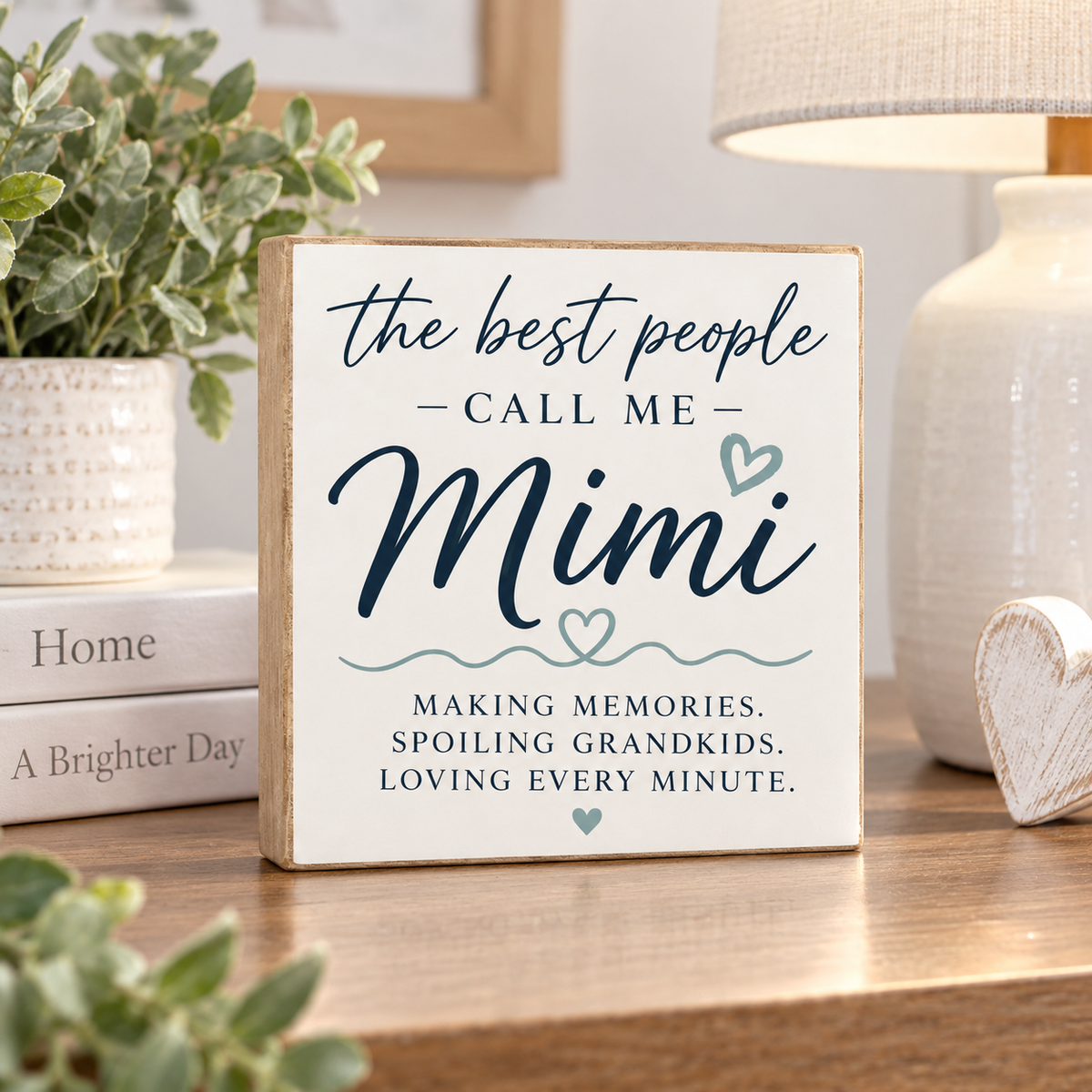 A square wooden sign with a white face and natural wood edges, reading 'the best people CALL ME Mimi' and 'MAKING MEMORIES. SPOILING GRANDKIDS.