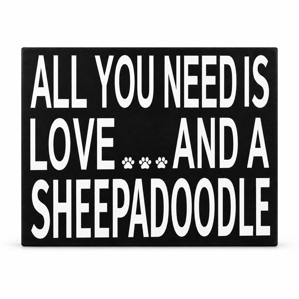 A rectangular black sign with bold white text reading 'ALL YOU NEED IS LOVE.
