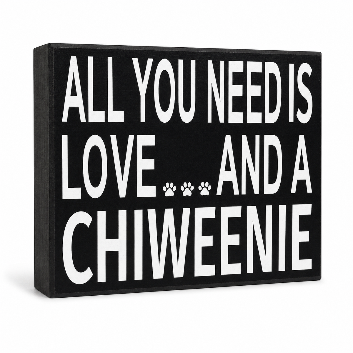 A rectangular black wall sign with bold white text reading 'ALL YOU NEED IS LOVE.