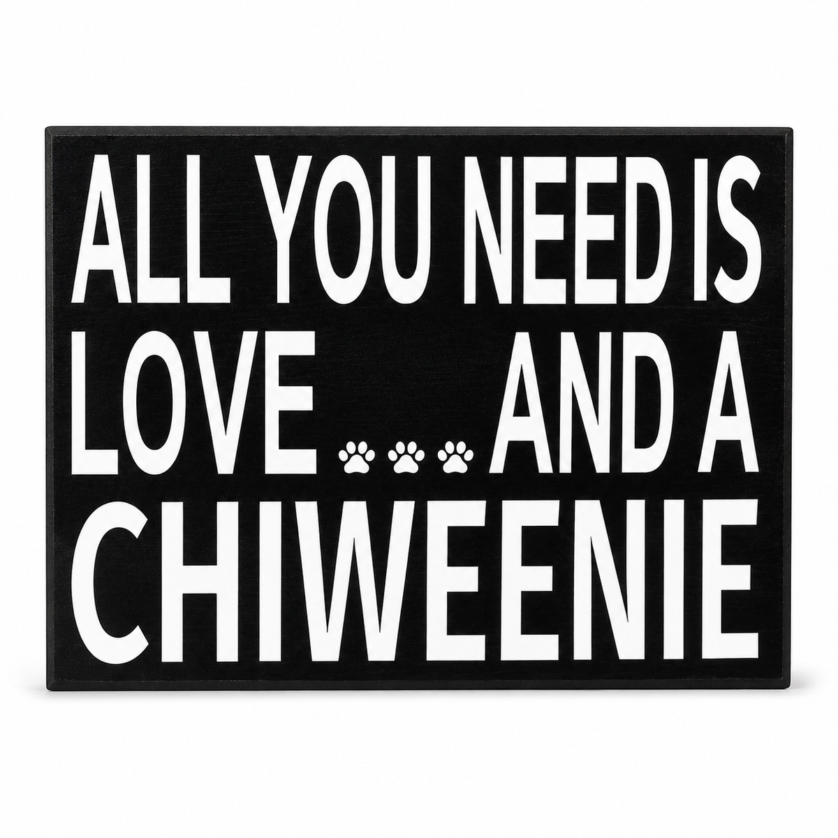 A rectangular black sign with bold white text reading 'ALL YOU NEED IS LOVE.