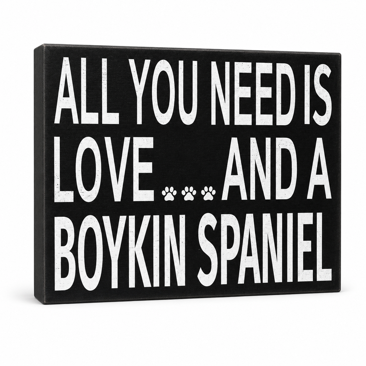 A rectangular black sign with bold white text reading 'ALL YOU NEED IS LOVE.