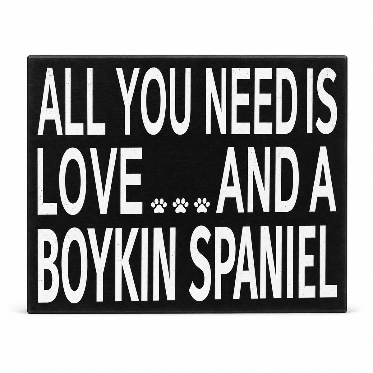 A rectangular black sign with bold white text reading 'ALL YOU NEED IS LOVE.