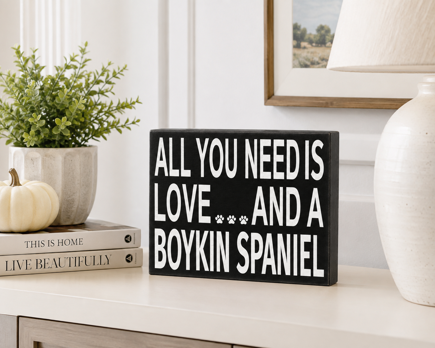 A rectangular black wooden sign with white text reading 'ALL YOU NEED IS LOVE.
