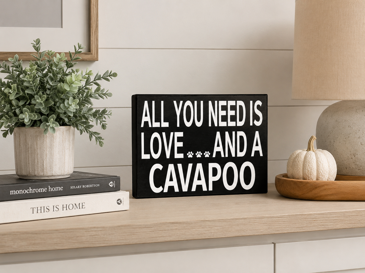 A black rectangular decorative sign with bold white text reading 'ALL YOU NEED IS LOVE.