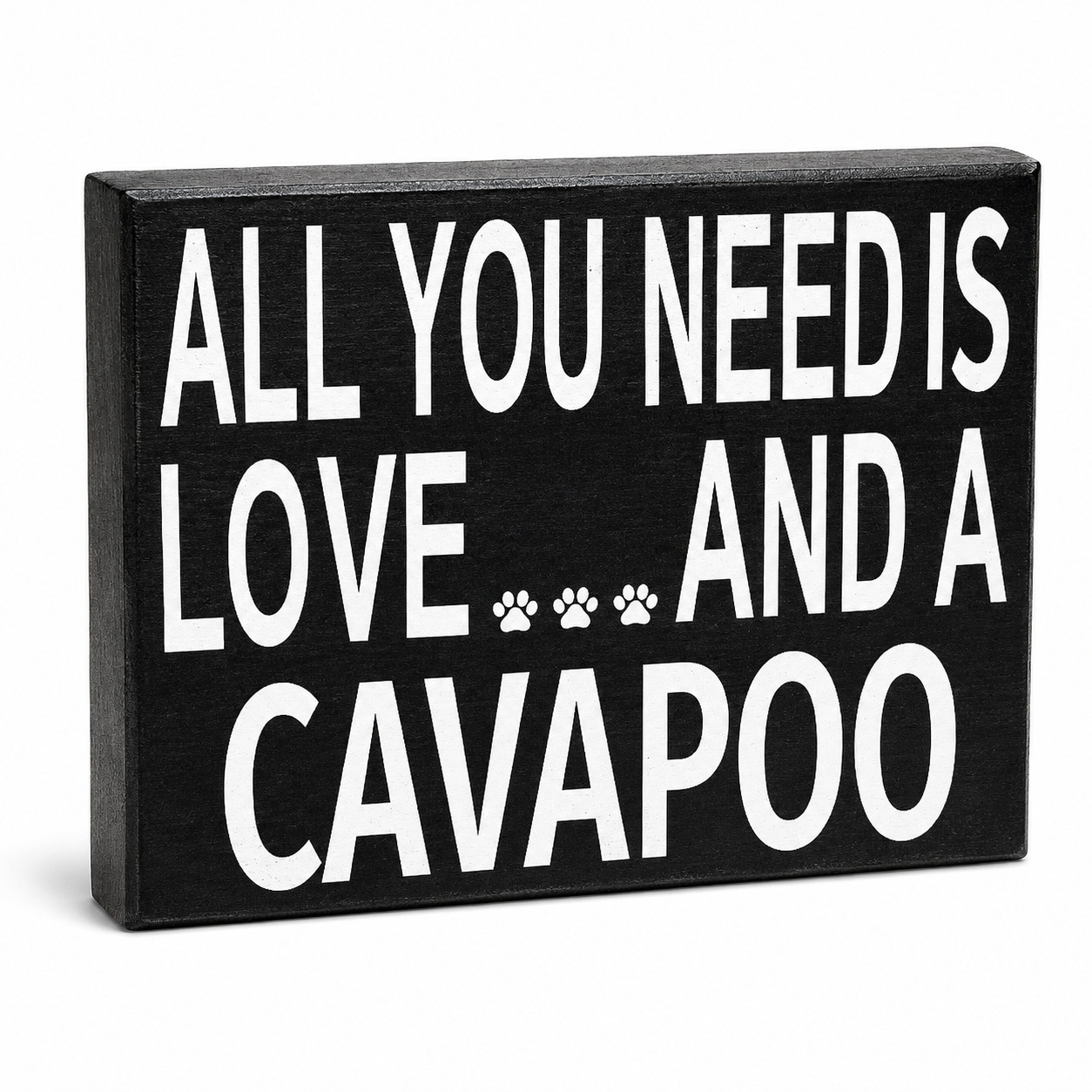 A rectangular black wooden sign with bold white text reading 'ALL YOU NEED IS LOVE.
