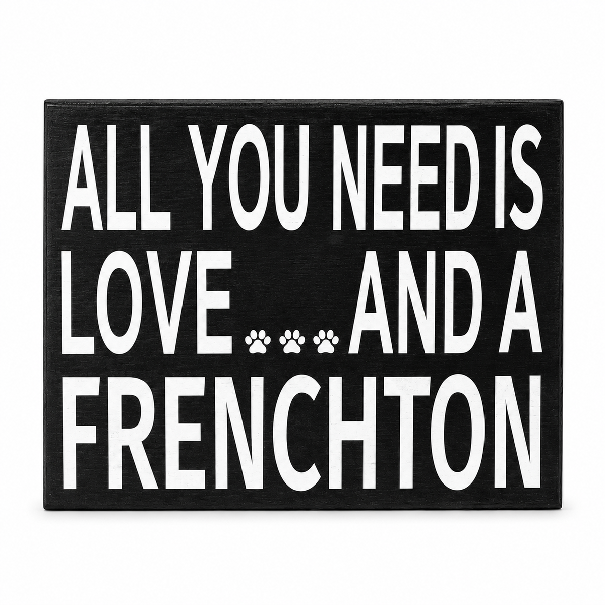 A rectangular black decorative sign with bold white text reading 'ALL YOU NEED IS LOVE.