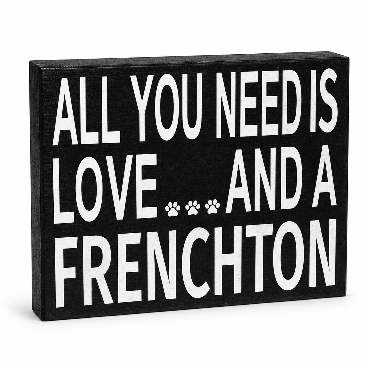 A rectangular black decorative sign with bold white text reading 'ALL YOU NEED IS LOVE.