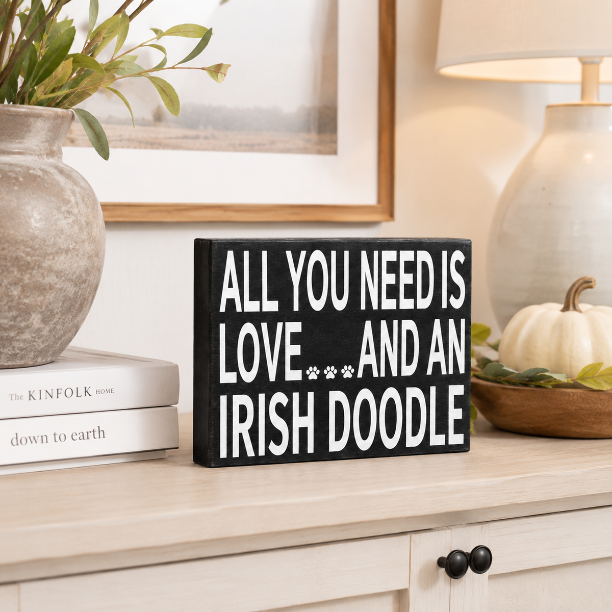 A rectangular black sign with bold white text reading 'ALL YOU NEED IS LOVE.