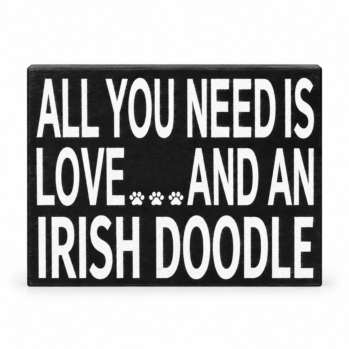A rectangular black wooden sign with bold white text reading 'ALL YOU NEED IS LOVE.