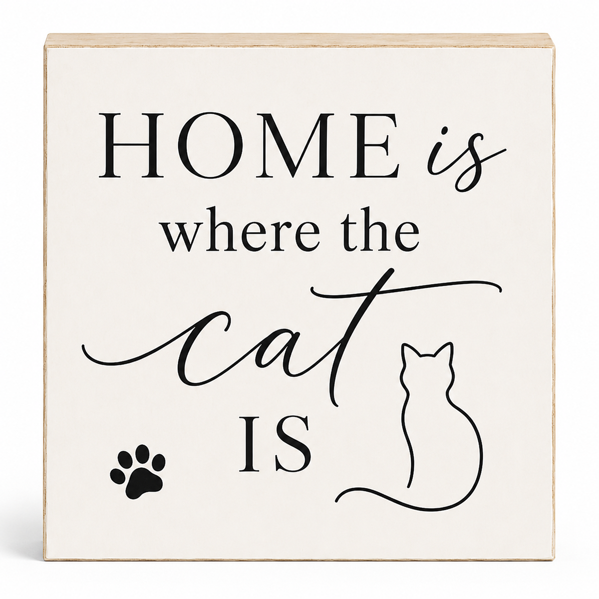 A square decorative wall sign with a light cream face and natural wood edges. The sign features the phrase 'HOME is where the cat IS' in black serif and script lettering, accompanied by a black cat silhouette outline, a black paw print, and a subtle drop shadow on a white background.