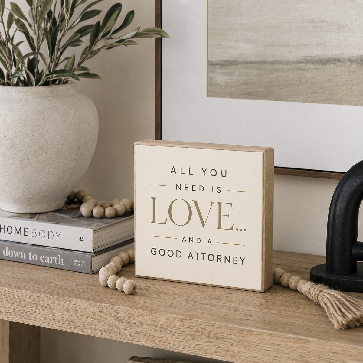 A square decorative wooden sign with the phrase 'ALL YOU NEED IS LOVE.