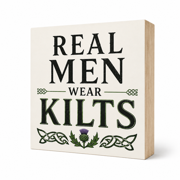 A square decorative wall sign with a light wood edge and an off-white face, printed with the phrase “REAL MEN WEAR KILTS” in large black and dark green lettering, plus Celtic knot and thistle graphics, shown on a white background.