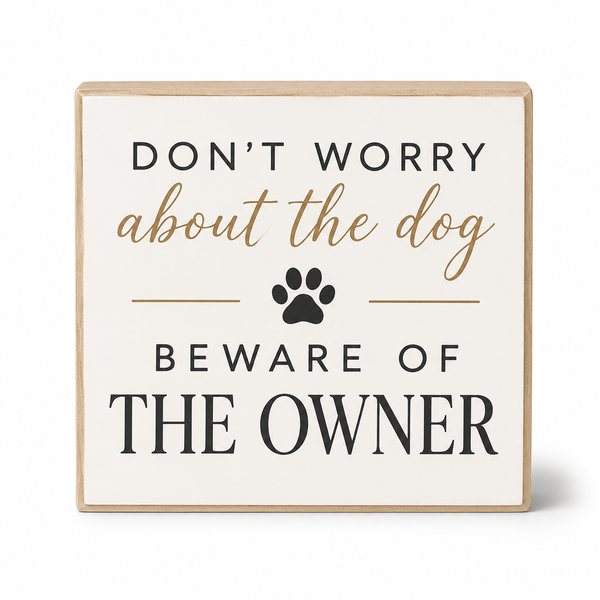 Square decorative wall sign with a light wood border and an off-white face. The sign reads “DON’T WORRY about the dog BEWARE OF THE OWNER” in black and tan lettering, with a black paw print in the center, on a white background.