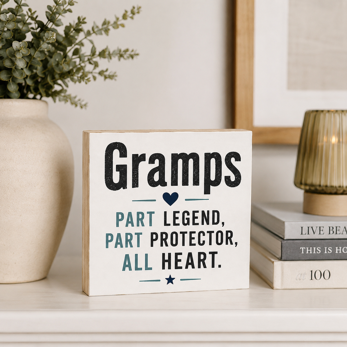 A square white wooden sign with a light natural wood border, featuring the text 'Gramps Part Legend, Part Protector, All Heart.' in black and teal lettering.