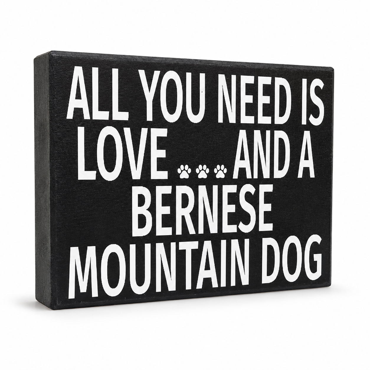 A rectangular black sign with bold white text reading 'ALL YOU NEED IS LOVE.