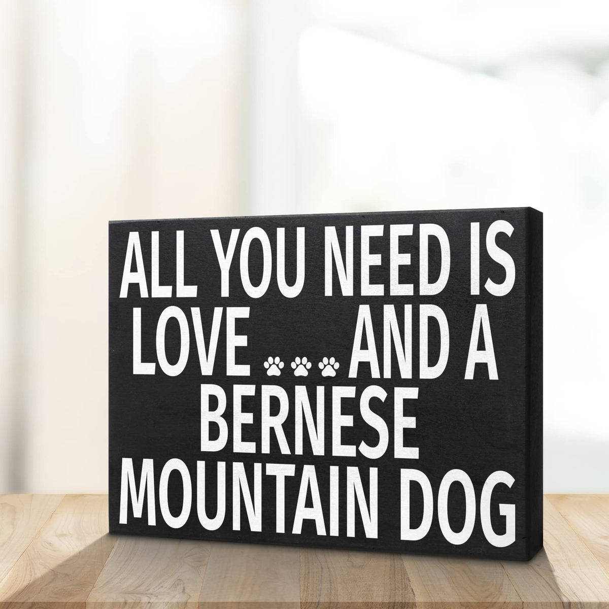 Decorative sign with text 'All you need is love and a Bernese Mountain Dog' on a wooden surface.