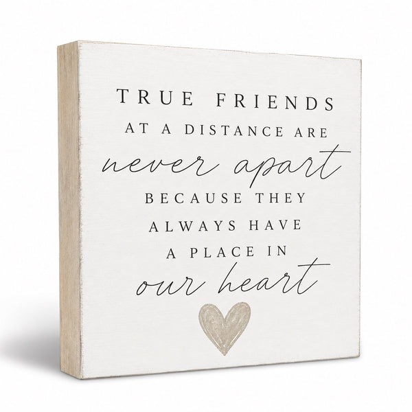 A square decorative wall sign with a distressed white face and natural wood side edges. The sign features a sentimental quote in black serif and cursive text, finished with a small textured gray heart at the bottom.
