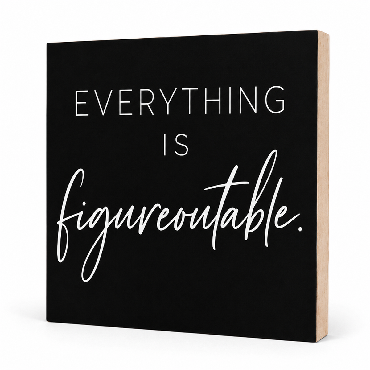 A square black decorative sign with white text reading 'EVERYTHING IS figureoutable.' shown at a slight angle to reveal a natural wood side edge, on a white background.
