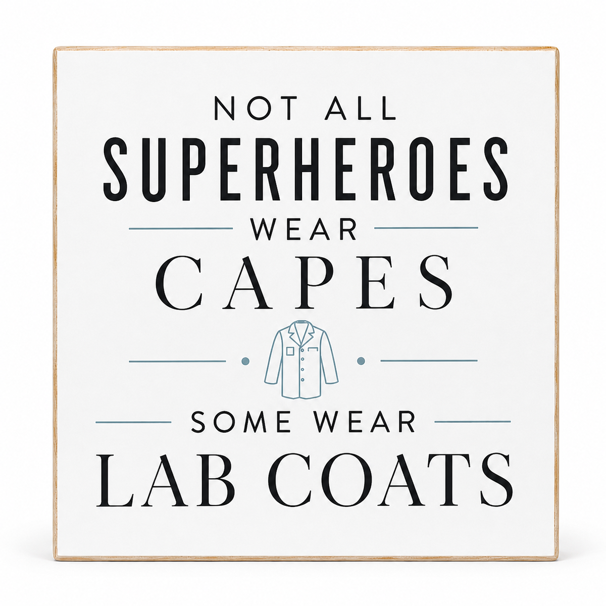 A square decorative sign with a light wood border and a white background. The sign features the text 'NOT ALL SUPERHEROES WEAR CAPES SOME WEAR LAB COATS' in black lettering, with a small light blue illustration of a lab coat in the center.