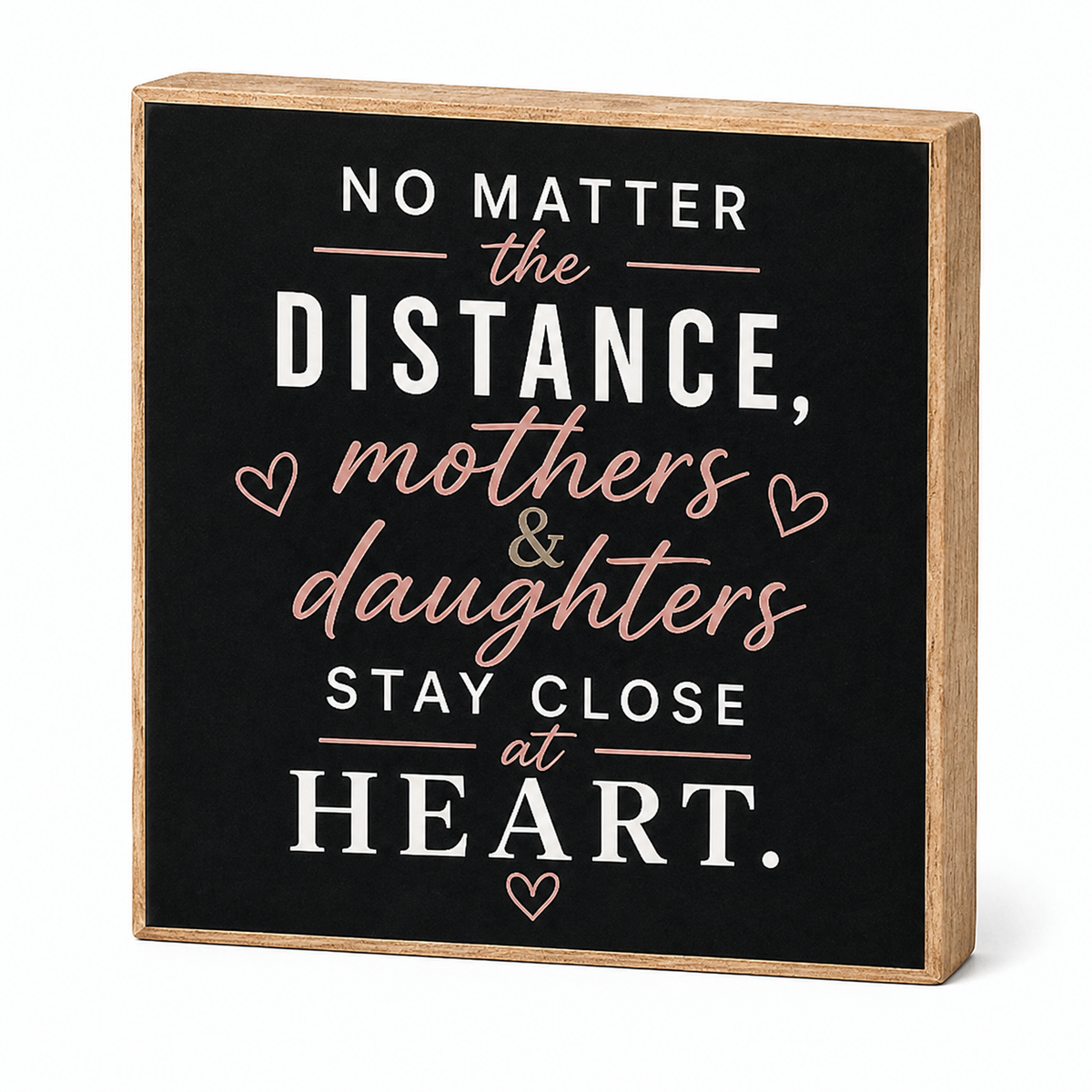 A square decorative wooden sign with a black face and natural wood edges, featuring the quote 'NO MATTER the DISTANCE, mothers & daughters STAY CLOSE at HEART.' in white and blush pink lettering with small heart accents, shown on a white background.
