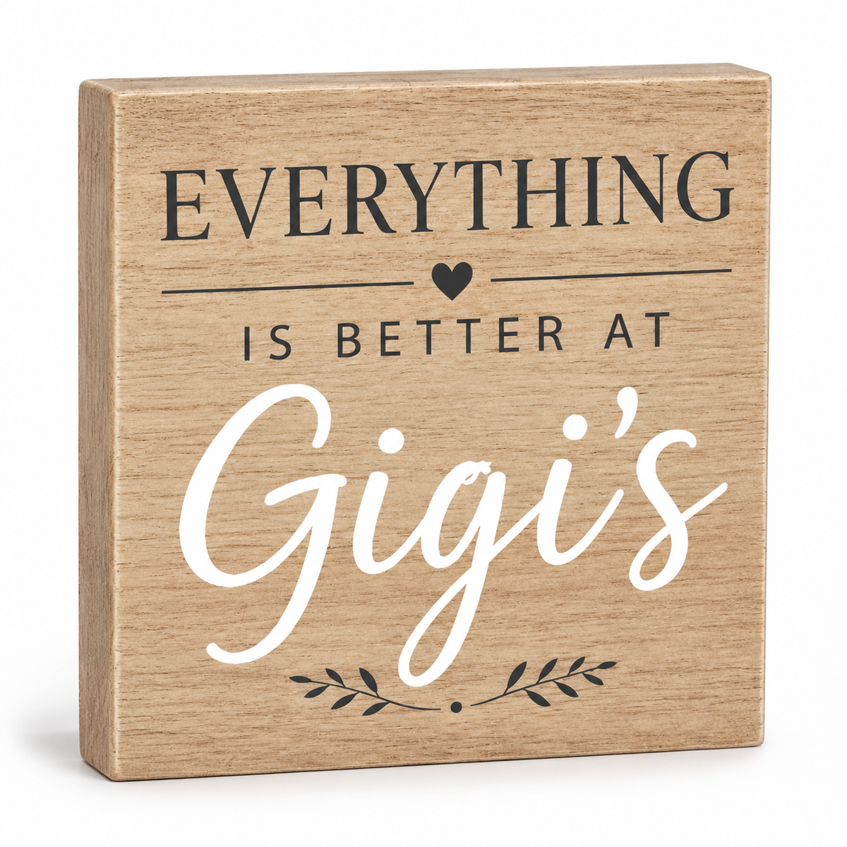 A square wooden block sign with a natural oak finish, featuring the printed text 'EVERYTHING IS BETTER AT Gigi's' in black and white lettering, set against a clean white background.