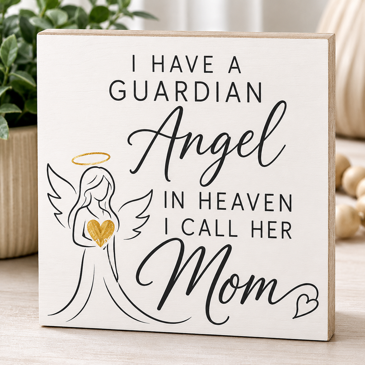 Decorative sign with angel illustration and text on a wooden block.