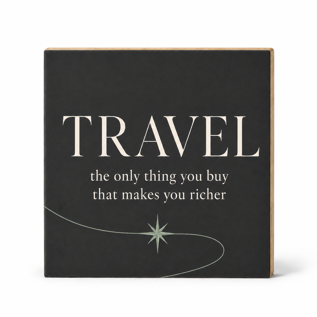 A square decorative wall sign with a dark charcoal face and natural wood edges. The sign features the word 'TRAVEL' in large cream serif letters, followed by the quote 'the only thing you buy that makes you richer' in smaller cream text.