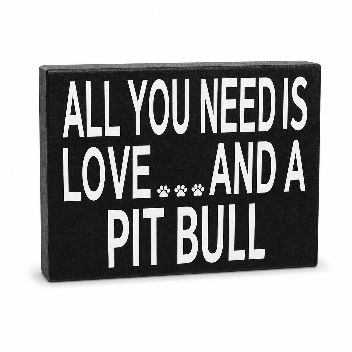 A rectangular black decorative sign with bold white text reading 'ALL YOU NEED IS LOVE.