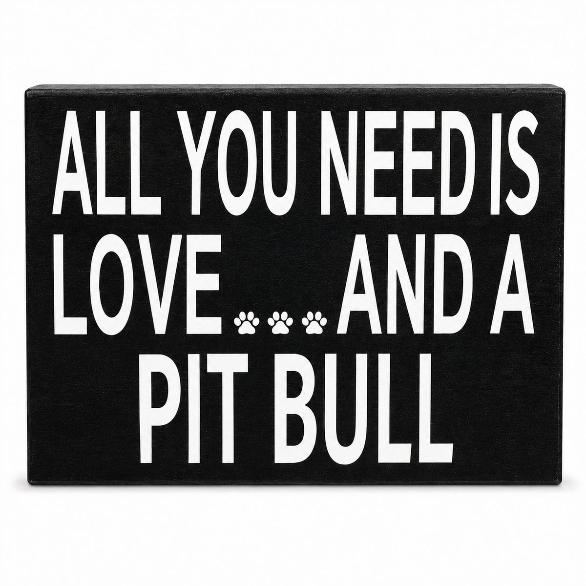 A rectangular black sign with bold white text reading 'ALL YOU NEED IS LOVE.