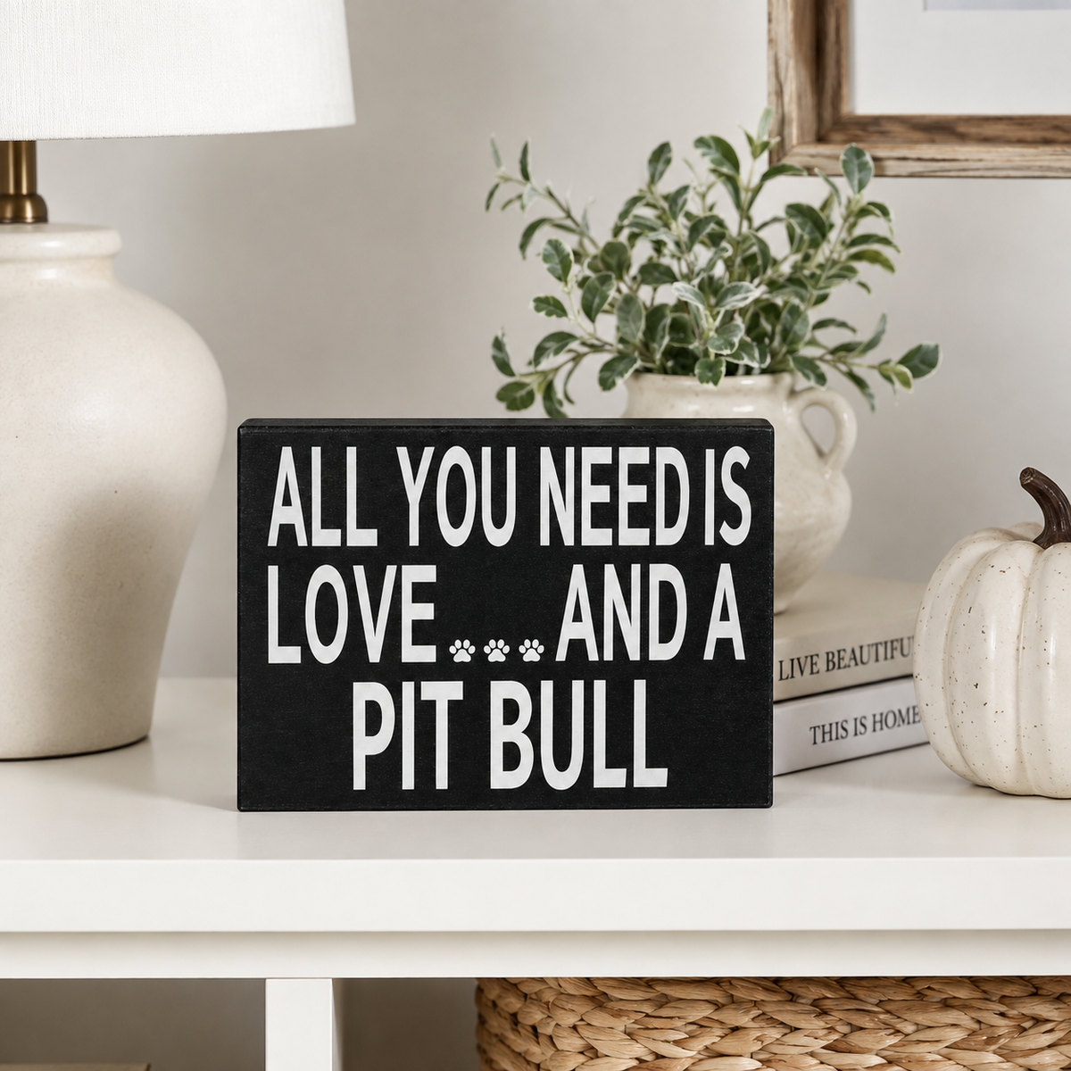 A black rectangular decorative sign with white text reading 'ALL YOU NEED IS LOVE.
